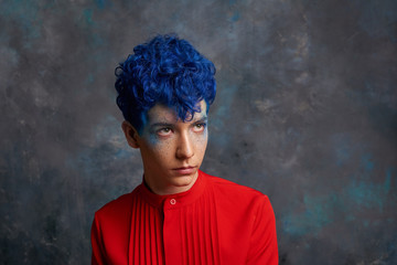 Portrait of a fashionable young guy in a tap-suit and a colorful blue hairstyle