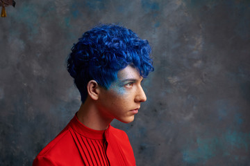 Portrait of a fashionable young guy in a tap-suit and a colorful blue hairstyle