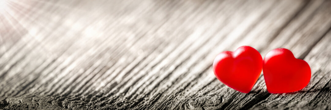 Two Soft Red Hearts On Vintage Wooden Table With Sunlight
