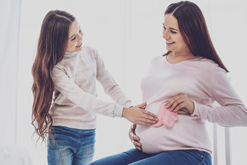 Happy preteen girl rubbing pregnant mothers belly