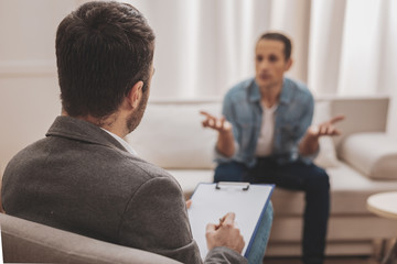 Psychologist wearing grey jacket listening to his anxious client