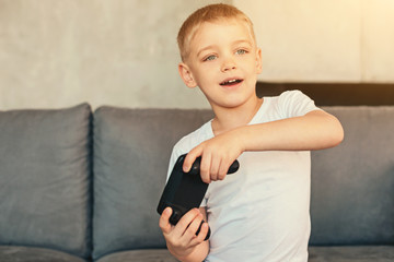 Cute fair-haired boy playing video game