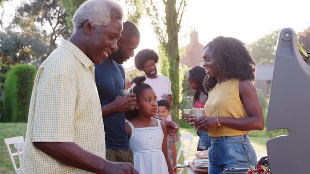 Grandad grilling at multi generation black family barbecue