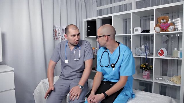 Male doctor and young intern in a good mood talking about new medical researchs