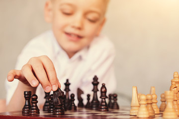 Little boy moving knight across chessboard - obrazy, fototapety, plakaty