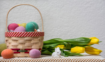 Easter basked and bunnies decorated with yellow tulips against white background copy space