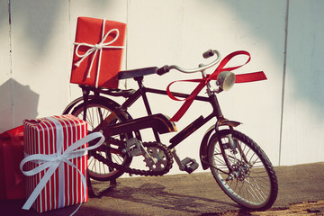 Group of elegant red gift box stack decorated with vintage toy bicycle on wood background, vibrant valentine lovely present concept