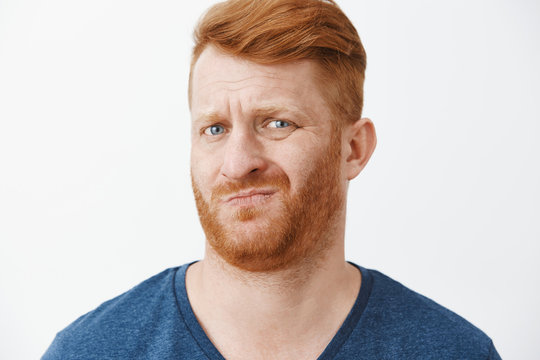 Sounds Suspicious And Gross. Portrait Of Unsure Displeased Funny Redhead With Cool Hairstyle, Frowning, Smirking And Wrinkling Nose From Dislike, Looking Doubtful At New Meal Wife Made