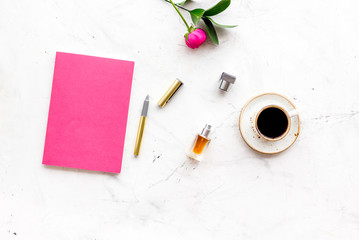Feminine desk. Notebook and stationery near pink flowers and coffee on white background top view