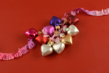 Valentine's Day heart ornaments on pink ribbon on red wooden background