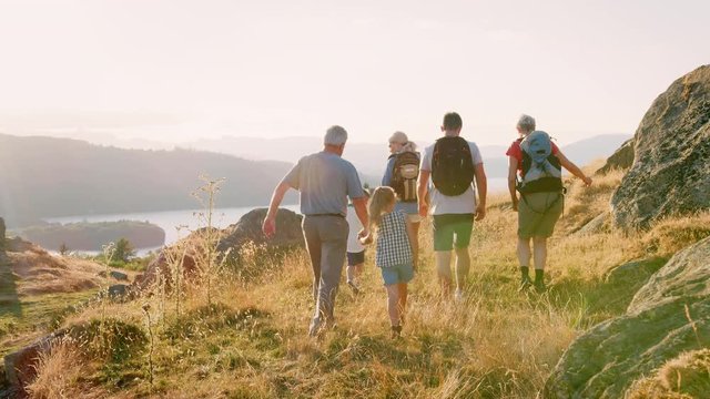 Slow Motion Rear View Shot Of Multi Generation Family Walking On Top Of Hill On Hike Through Countryside In Lake District UK 
