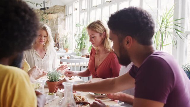 A multi ethnic, mixed age group of adult friends eating tapas together at a table in a restaurant, close up, selective focus