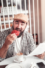 Man eating a delicious red croissant in the cafe