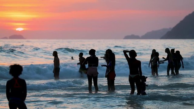 Woman with children enjojing waves in sand beach on sunset, Leblon, Copacabana, Rio de Janeiro, Brazil