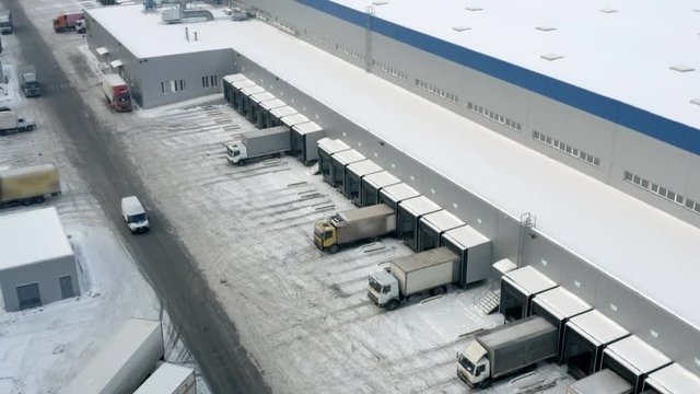 Aerial view of a logistics hub with a semi-trailers trucks standing at warehouse  ramp load/unload goods