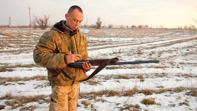 Winter hunting for hares. Hunter charges the cartridges in the gun.
