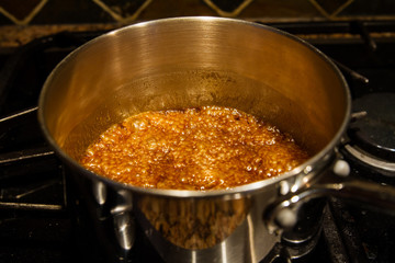 Homemade caramel in a pot on a stove; caramel boiling and ready to pour over popcorn or to make other sweets