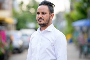 Bearded Indian businessman thinking in the streets outdoors