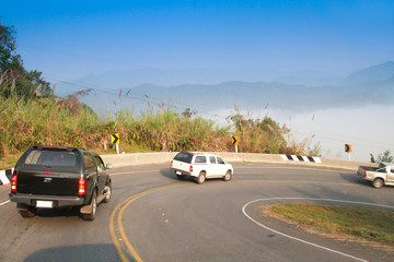 Fototapeta na wymiar driving on curve road in the mountain with the sea mist and blue sky and forest, country road in north of Thailand