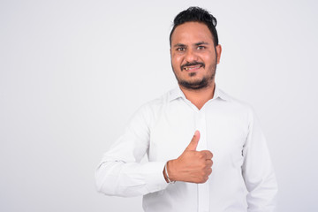 Studio shot of happy bearded Indian businessman giving thumbs up