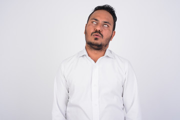 Studio shot of stressed bearded Indian businessman looking bored and tired