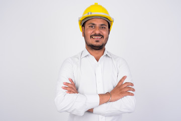 Happy bearded Indian businessman wearing hardhat with arms crossed