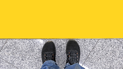 Man in modern fashion shoes and jeans standing on edge of yellow wait line abstract top down aerial view background city transportation travel street fashion concept casual lifestyle landscape scene