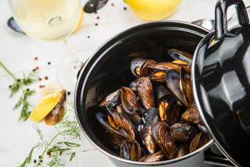 Fototapeta premium mussels in white wine sauce with glass of white wine , decorated with herbs, lemon and pepper