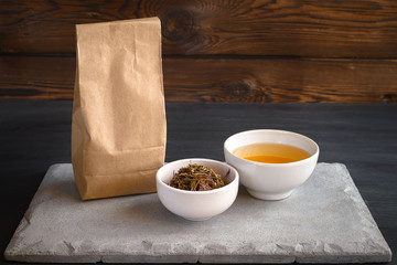 Herbal tea in cup. A paper bag of herbs and a cup of hot drink. Wooden background