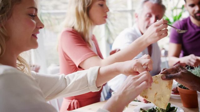 A mixed age group of adult friends sharing tapas at a table in a restaurant, selective focus, focus on foreground