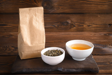 Herbal tea in cup. A paper bag of herbs and a cup of hot drink. Wooden background