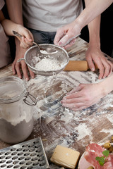Obraz na płótnie Canvas Mom with children preparing the dough for homemade pizza.