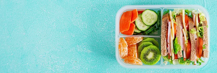 Selbstklebende Fototapete Produktauswahl Schulbrotdose mit Sandwich, Gemüse, Wasser und Obst auf dem Tisch. Konzept für gesunde Essgewohnheiten. Flach liegen. Banner. Ansicht von oben