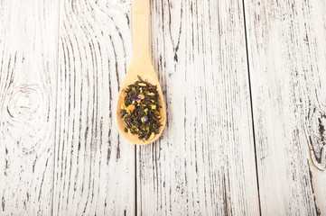 Organic black and green tea on a wooden spoon close-up on a white textural table