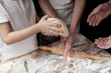 Obraz na płótnie Canvas Mom with children preparing homemade pizza in the kitchen.