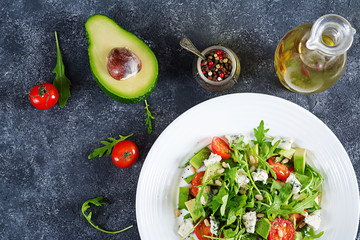 Dietary salad with tomatoes, blue cheese, avocado, arugula and pine nuts. Top view. Flat lay.