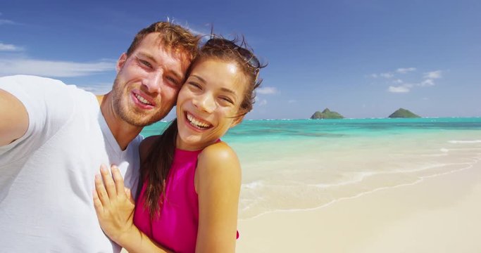 Selfie video. Couple on beach vacation taking selfie photograph using smart phone. Romantic couple in love on honeymoon having fun on Lanikai beach, Oahu, Hawaii, USA. RED EPIC SLOW MOTION.
