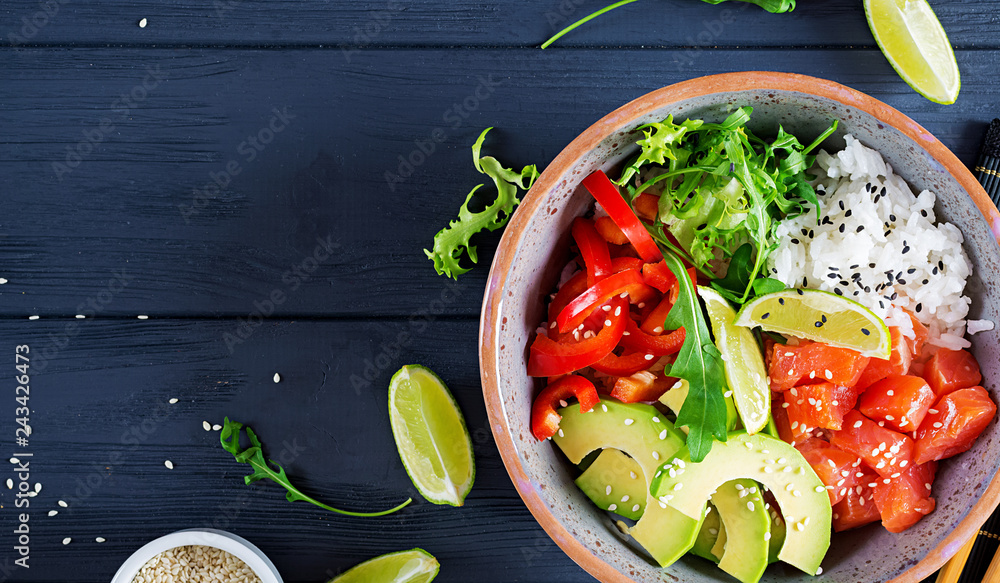 Wall mural Hawaiian salmon fish poke bowl with rice, avocado, paprika, sesame seeds and lime. Buddha bowl. Diet food. Top view