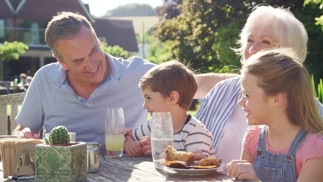 Grandparents With Grandchildren Enjoying Outdoor Summer Pub Lunch