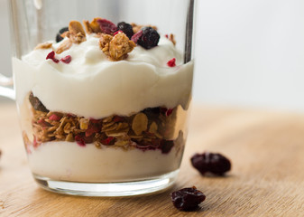 yogurt and muesli (crunchy, granola) in layers in a glass cup, closeup