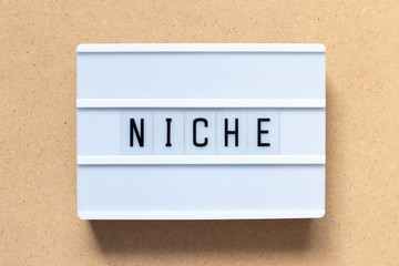 White lightbox with word niche on wood background