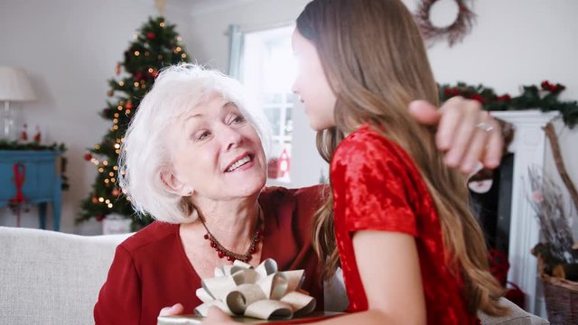 Grandmother Receiving Christmas Gift From Granddaughter At Home