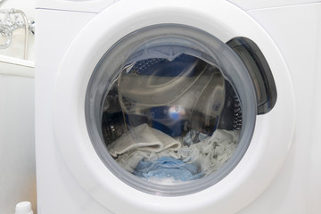 Drum washing machine with wet laundry, close-up.
