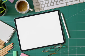 Mockup blank screen tablet and graphic designer supplies on green cutting mat