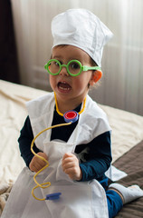 2 year old boy playing doctor with funny face.