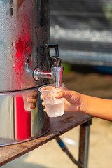 Hand boy holding the glass with water from the water cooler.