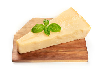 A piece of aged Parmesan cheese on a wooden cutting board with fresh basil leaves on a white background with a place for text