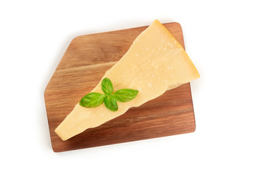 A piece of aged Parmesan cheese, shot from the top on a wooden cutting board with fresh basil leaves on a white background with a place for text