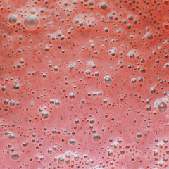 Closeup of fresh pink smoothie or cocktail as textured background. Healthy and tasty food concept.