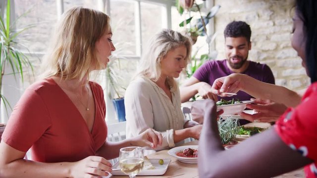 Young adult friends sharing tapas dishes for lunch at a restaurant table, selective focus